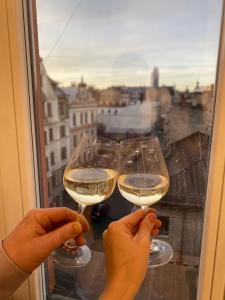 2 personnes tenant des verres à vin devant une fenêtre dans l'établissement Golden Rush, à Riga
