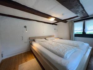 een slaapkamer met een groot bed met witte lakens bij Ferienhaus Gemütliche Stube in Überlingen