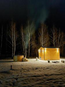 a small wooden shed in the snow at night at Domek na Roztoczu Sauna & Jacuzzi in Horyniec