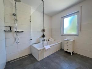 a bathroom with a shower and a tub and a sink at Ferienwohnung am Tobelbach in Überlingen +22 photos