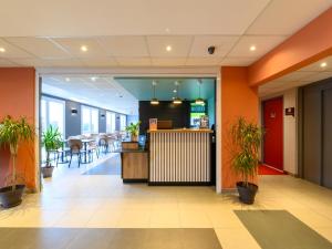 un hall de bureau avec des murs orange et des plantes en pot dans l'établissement B&B HOTEL Compiègne Thourotte, à Thourotte
