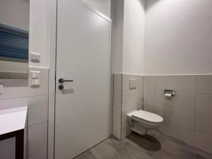 a white bathroom with a toilet and a door at Landhaus zum See - Fewo Birke in Überlingen