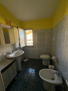 uma casa de banho com 2 lavatórios e um WC e paredes amarelas em Berchida 1 em La Caletta