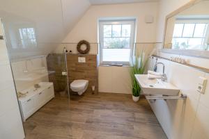 a bathroom with a toilet and a sink and a shower at Ferienhaus Meerträume in Pewsum +24 photos