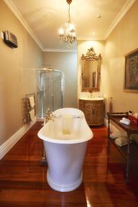 a bathroom with a large white tub and a mirror at Escape To Picton Boutique Hotel in Picton