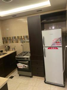 a kitchen with a stove and a white refrigerator at شقة فندقية غرفتين للايجار بالمهندسين in Cairo