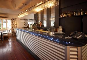 a woman sitting at a bar in a restaurant at Escape To Picton Boutique Hotel in Picton