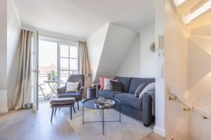 ein Wohnzimmer mit einer blauen Couch und einem Tisch in der Unterkunft Hingst, App. 3 Nettes Neest in Wenningstedt-Braderup