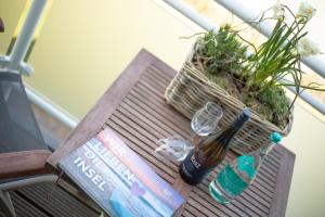 einen Holztisch mit einer Flasche und Brille sowie ein Buch in der Unterkunft Hingst, App. 3 Nettes Neest in Wenningstedt-Braderup
