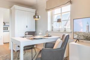 ein Esszimmer mit einem weißen Tisch und Stühlen in der Unterkunft Hingst, App. 3 Nettes Neest in Wenningstedt-Braderup