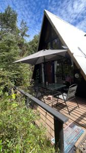una casa con una mesa y una sombrilla en una cubierta en Refugio de bosque altos de ñancul, en Panguipulli