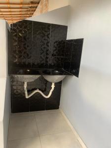 La salle de bains est pourvue d'un lavabo et d'un mur en carrelage noir. dans l'établissement Apartamento confortável, à Boa Vista
