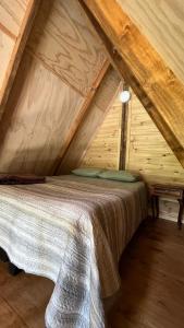 Cama en el ático de una casa de madera en Refugio de bosque altos de ñancul, en Panguipulli