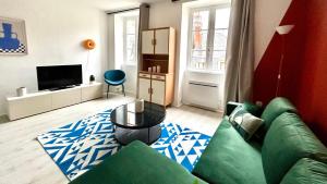 a living room with a green couch and a television at Le Terracotta in Nevers