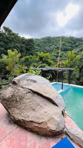 un grand rocher assis à côté d'une piscine dans l'établissement Cabaña la roca de minca sierra nevada, à Santa Marta