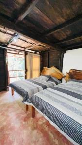 3 camas están alineadas en una habitación en Cabaña la roca de minca sierra nevada, en Santa Marta