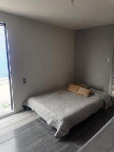uma cama num quarto com uma grande janela em Habitación cómoda y tranquila em Cidade do México