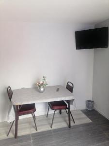 een tafel met twee stoelen en een televisie aan de muur bij Habitación cómoda y tranquila in Mexico-Stad
