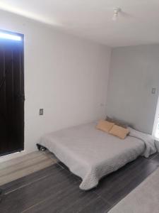 um quarto com uma cama num quarto branco em Habitación cómoda y tranquila em Cidade do México