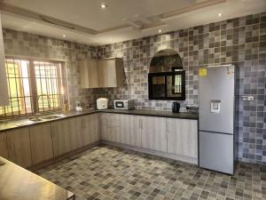 a kitchen with a white refrigerator and tile walls at Medi Square Lodge in Freetown