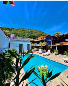 un complejo con una piscina y una montaña en el fondo en Pousada Porto Praia, en Arraial do Cabo