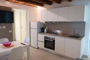 uma cozinha com electrodomésticos brancos, uma mesa e uma mesa; em Iris House em Chioggia