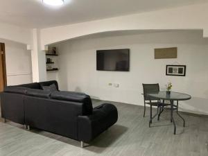 ein Wohnzimmer mit einem schwarzen Sofa und einem Tisch in der Unterkunft Departamento 2 habitaciones in Chitré