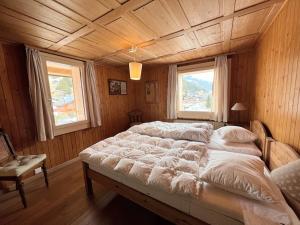 duże łóżko w drewnianym pokoju z 2 oknami w obiekcie ZE Mountain Lodge, Morgins w mieście Morgins