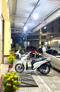 une moto garée dans un garage avec des voitures garées dans l'établissement NHÀ NGHỈ NAM PHƯƠNG, à Hà Tiên
