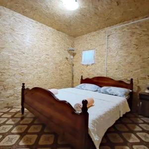 a bedroom with a wooden bed in a stone wall at Kucica Truma in Ulcinj