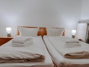 een slaapkamer met 2 bedden met witte lakens en handdoeken bij "Deichmöwe" im Möwennest Greetsiel in Krummhörn