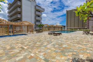 eine Terrasse mit Bänken und einem Pool in einem Gebäude in der Unterkunft Escape to Paradise, Ocean & Diamond Head View Studio in Waikiki! in Honolulu