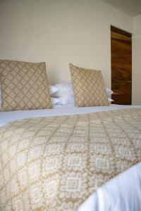 una camera da letto con un grande letto con due cuscini di Villa Quetzalpapalotl a Pérula
