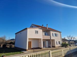 une maison blanche avec une clôture devant elle dans l'établissement House Iva Luca, à Radošinovac