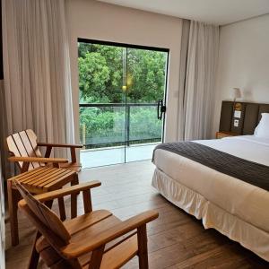 Habitación de hotel con cama, 2 sillas y ventana en Pousada Menino de Ouro, en Penedo