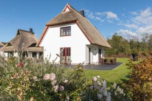 een wit huis met een rieten dak bij Haus Rose, Luxus-Ferienhaus in Fuhlendorf fur 4 Personen in Fuhlendorf