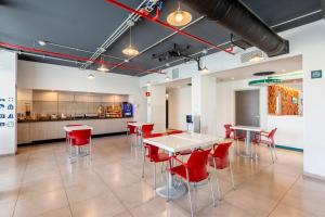 a dining room with red chairs and a white table at City Express Junior by Marriott Merida Altabrisa in Mérida