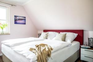een slaapkamer met een wit bed met een rood hoofdeinde bij Haus Rose, Luxus-Ferienhaus in Fuhlendorf fur 4 Personen in Fuhlendorf