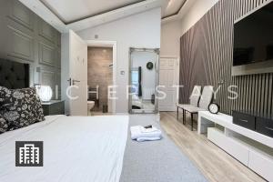 1 Schlafzimmer mit einem großen Bett und einem Badezimmer in der Unterkunft Hackney Suites - En-suite rooms & amenities in London