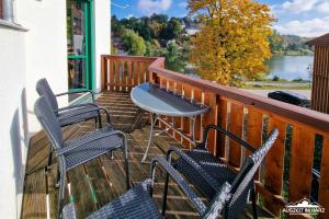 einen Balkon mit Stühlen und einem Tisch sowie Seeblick in der Unterkunft Auszeit-im-Harz Haus 5 Wohnung 32 in Stiege