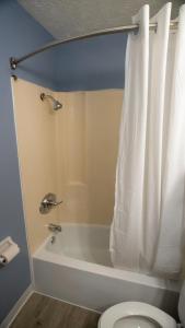bagno con vasca e servizi igienici con tenda per la doccia. di Ashley Motel a Plainfield