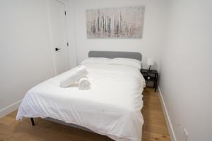 um quarto branco com uma cama com lençóis brancos em Beautifully Renovated 3BR Downtown 2min to METRO em Montreal