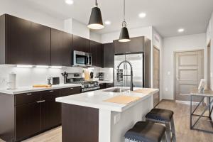 eine Küche mit weißer Arbeitsplatte und braunen Schränken in der Unterkunft Stunning Westgate CozySuites by stadium with pool 10 in Glendale + 22 Fotos