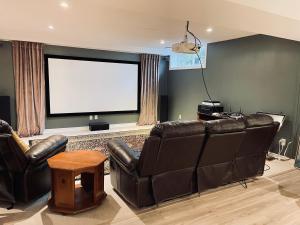 a living room with leather furniture and a large screen at Golf Viwe house in Ottawa