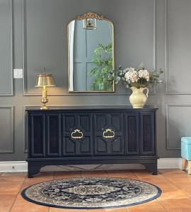 a black dresser with a mirror and a vase with flowers at Golf Viwe house in Ottawa