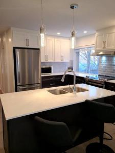 a kitchen with a sink and a refrigerator at Cozy haven near Olympic Park, Pac-Man Arcade Game in Montreal