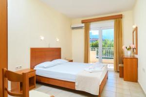 a bedroom with a large bed and a balcony at Ladikas apartments in Chrysi Ammoudia