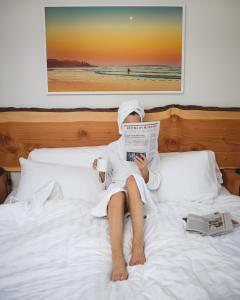 a person laying on a bed reading a newspaper at Pacific Sands Beach Resort in Tofino