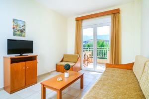 a living room with a couch and a tv at Ladikas apartments in Chrysi Ammoudia