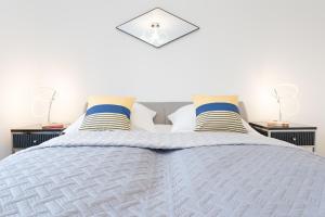 een slaapkamer met een wit bed met blauwe en gele kussens bij Pamirstraße 2 Seeluft in Niendorf